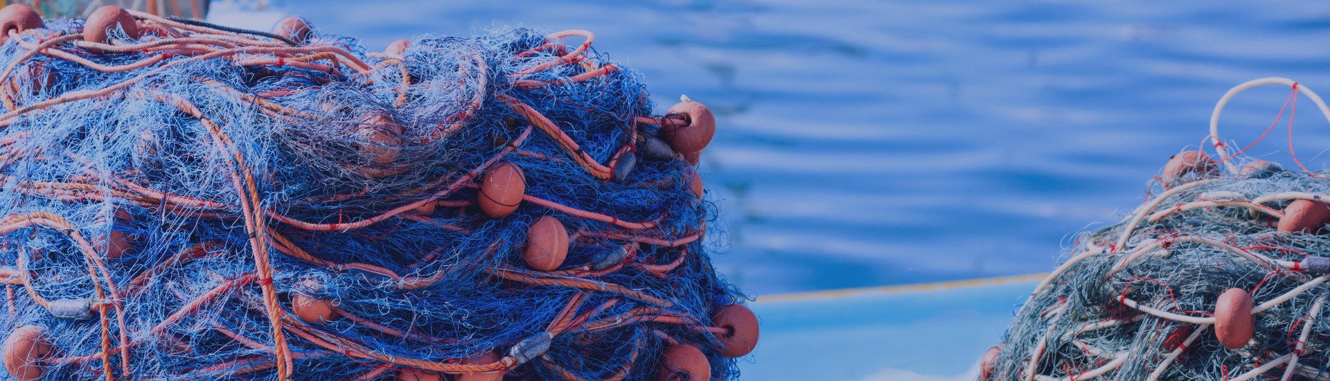 stacks-of-fishing-nets-on-blue-sea-water-PCQM92Y